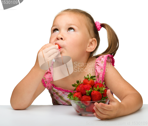 Image of Happy little girl eats strawberries