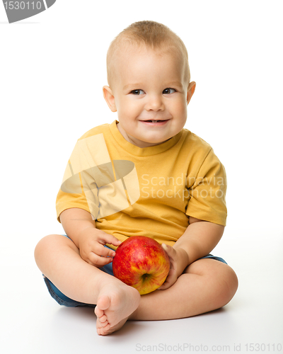 Image of Cheerful little boy with red apple