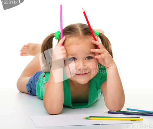 Image of Little girl is drawing while laying on the floor