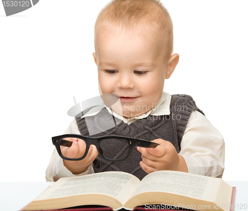 Image of Little child play with book and glasses