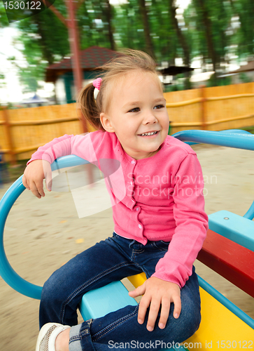 Image of Cute little girl is riding on merry-go-round