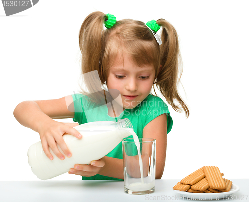 Image of Cute little girl is pouring milk in glass
