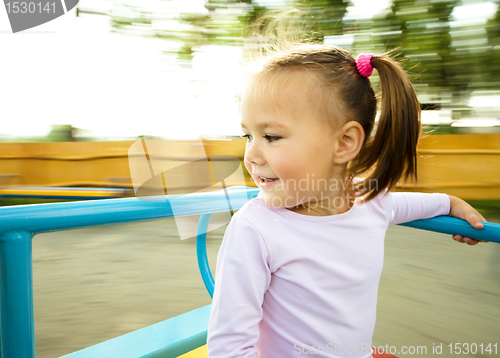 Image of Cute little girl is riding on merry-go-round