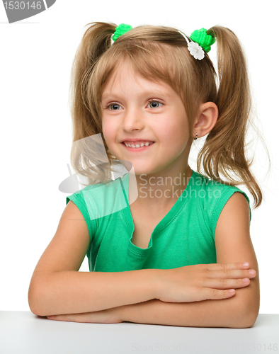 Image of Happy little girl is sitting at the table