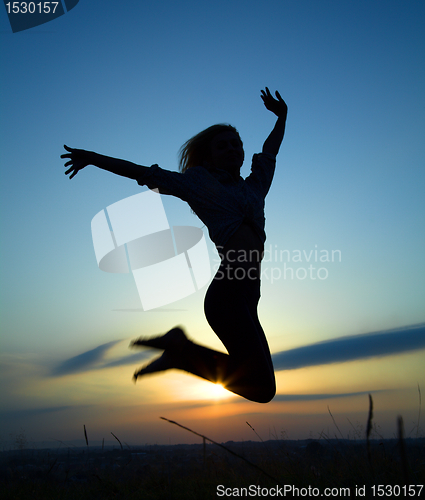 Image of Silhouette of a girl jumping over sunset