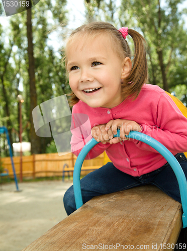 Image of Cute little girl is swinging on see-saw