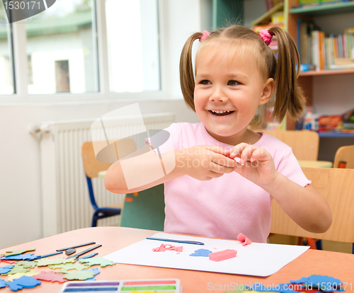 Image of Little girl is playing with plasticine