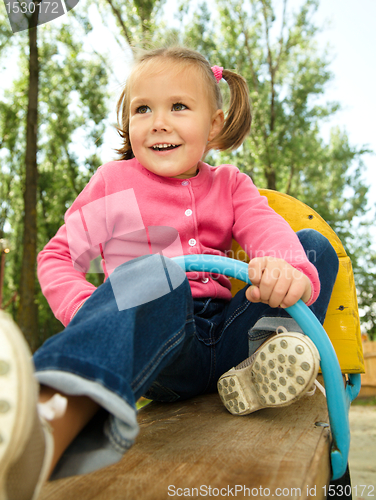 Image of Cute little girl is swinging on see-saw