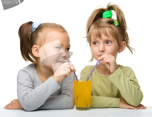 Image of Two little girls are drinking orange juice