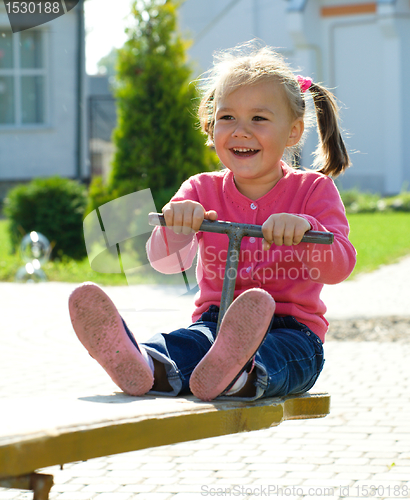 Image of Cute little girl is swinging on see-saw