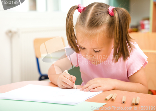 Image of Little girl is drawing with color pencils