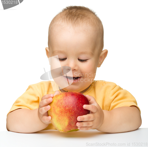 Image of Little child is biting red apple