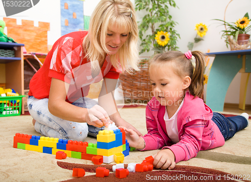 Image of Teacher and child are playing with bricks