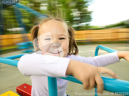 Image of Cute little girl is riding on merry-go-round