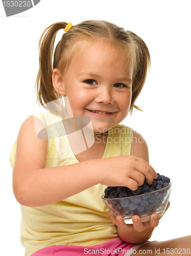 Image of Cheerful little girl is eating blueberry