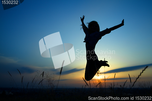 Image of Silhouette of a girl jumping over sunset