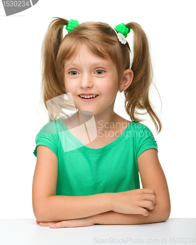 Image of Little girl is sitting at table in astonishment