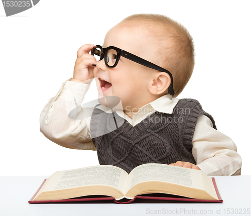 Image of Little child play with book and glasses