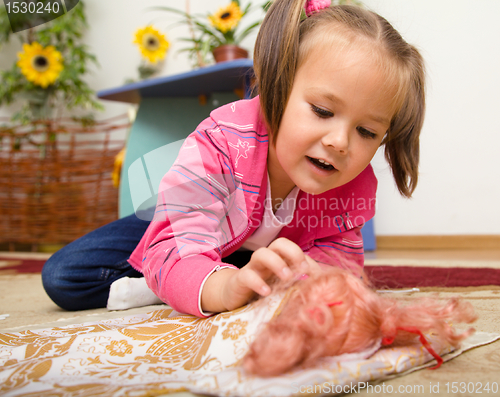 Image of Little girl is putting her doll to sleep