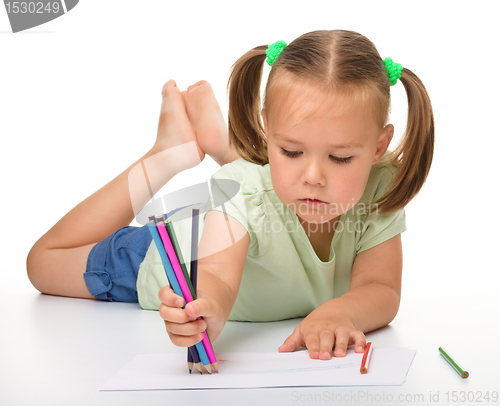 Image of Little girl is drawing while laying on the floor