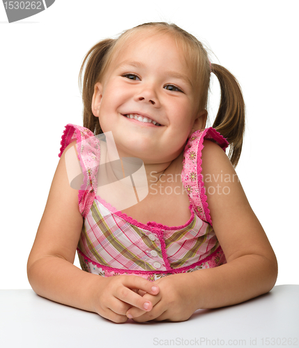 Image of Happy little girl is sitting at the table