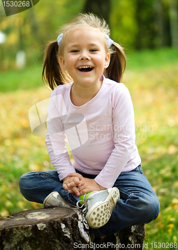 Image of Little girl is playing in autumn park