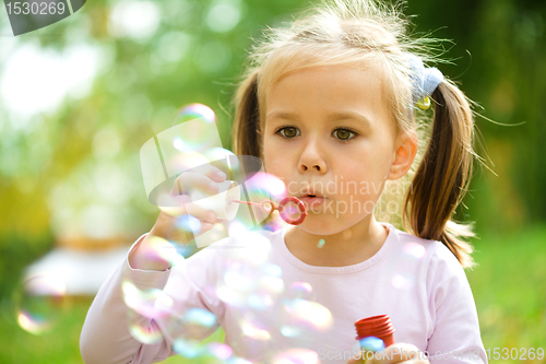 Image of Little girl is blowing a soap bubbles