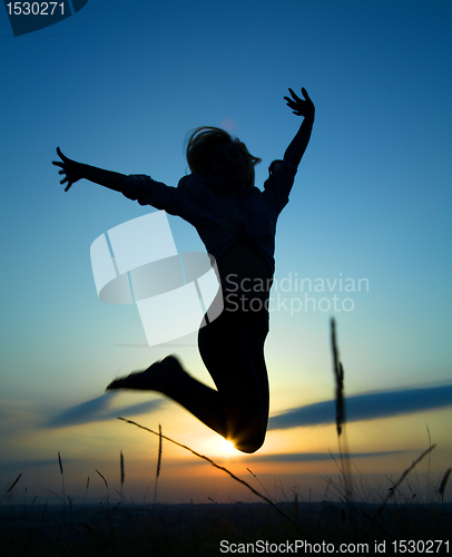 Image of Silhouette of a girl jumping over sunset