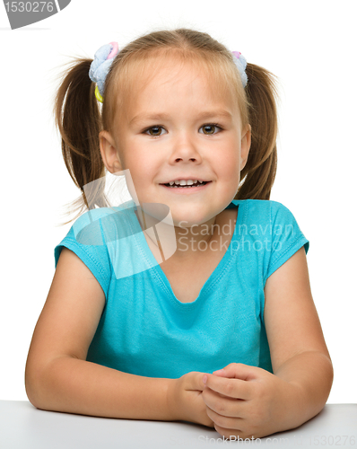 Image of Happy little girl is sitting at the table