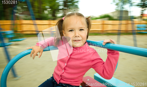 Image of Cute little girl is riding on merry-go-round