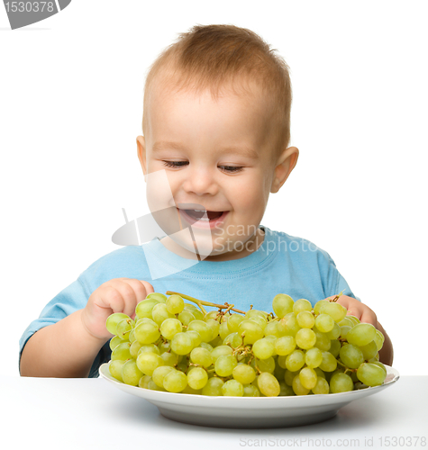 Image of Little boy is eating grapes