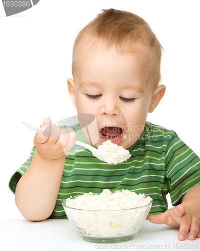 Image of Little boy is eating cottage cheese using spoon