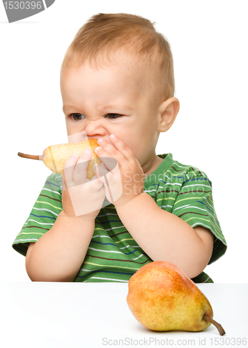 Image of Cute little boy is biting pear
