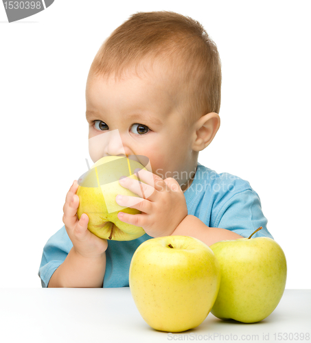 Image of Little boy biting yellow apple