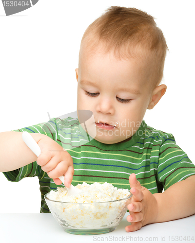 Image of Little boy is eating cottage cheese using spoon
