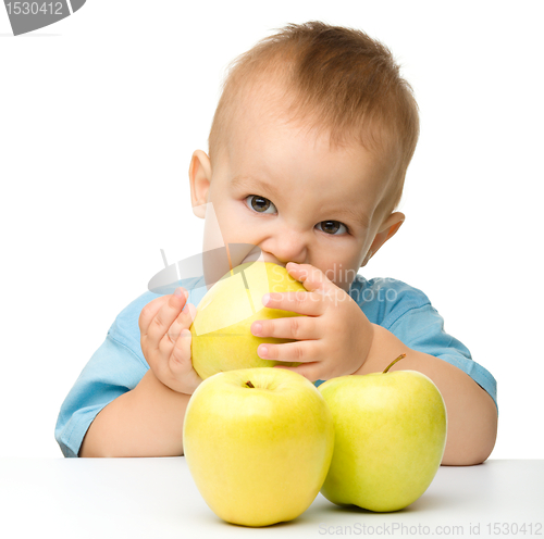 Image of Little boy biting yellow apple
