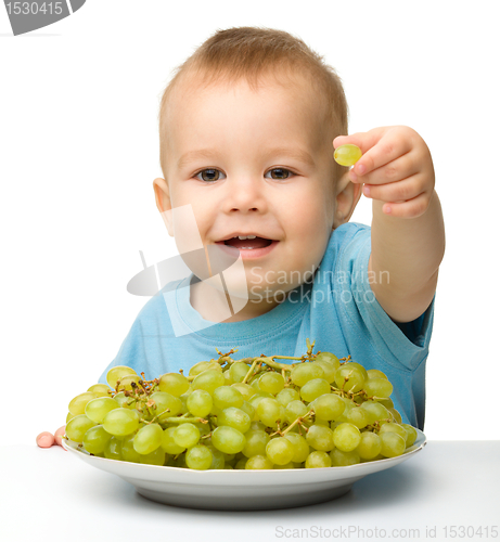 Image of Little boy is eating grapes