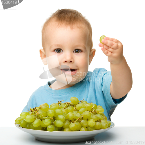Image of Little boy is eating grapes