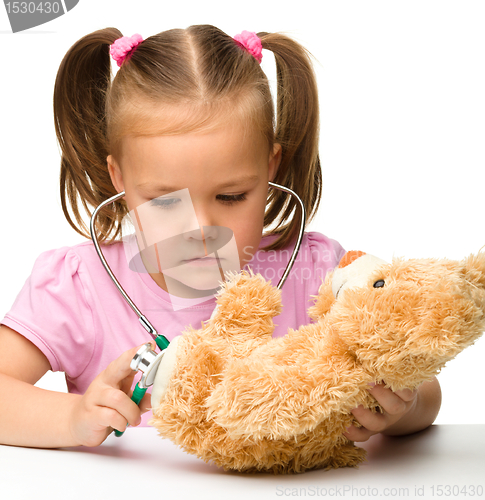 Image of Little girl is playing with her teddy bear