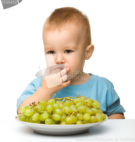 Image of Little boy is eating grapes