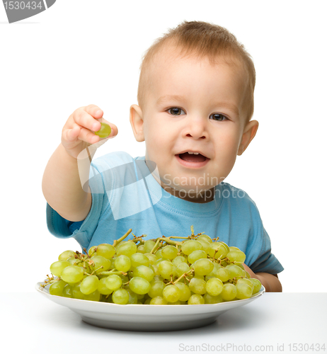 Image of Little boy is eating grapes