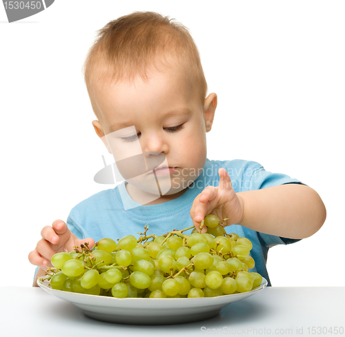 Image of Little boy is eating grapes