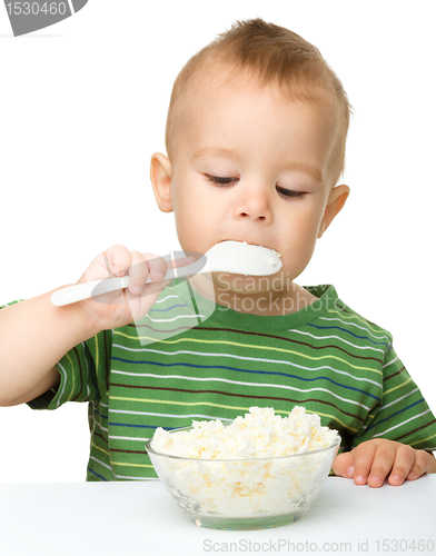 Image of Little boy is eating cottage cheese using spoon