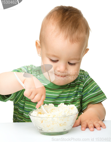Image of Little boy is eating cottage cheese using spoon