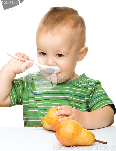 Image of Cute little boy with pears is biting spoon
