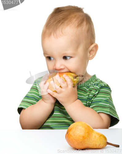 Image of Cute little boy is biting pear
