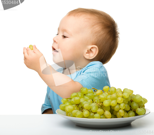 Image of Little boy is eating grapes