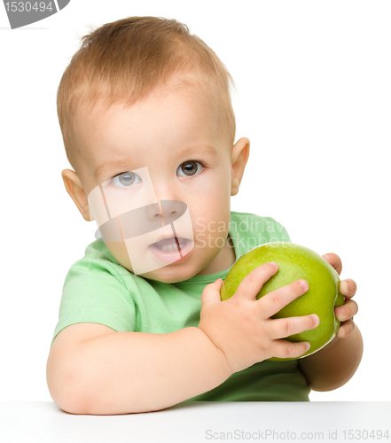 Image of Little child is eating green apple