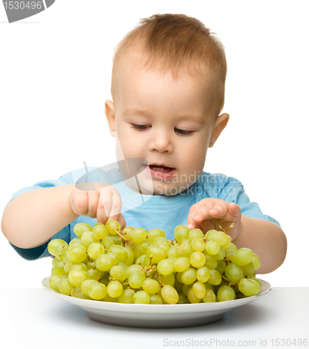 Image of Little boy is eating grapes