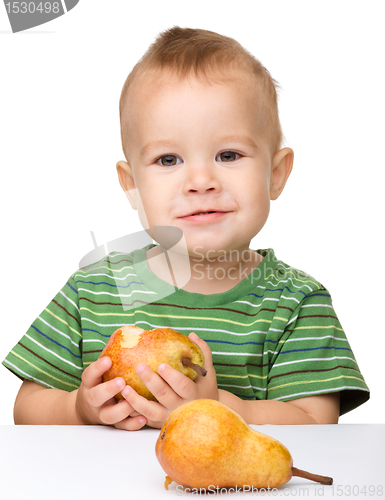 Image of Cute little boy is eating pear